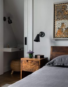 a bedroom with a bed, nightstand and painting on the wall above it's headboard