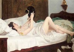 a woman laying on top of a bed next to a cat