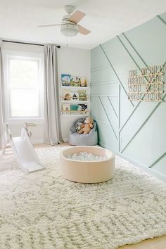 a baby's room with a white rug and blue walls, including a play area