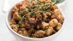 a white bowl filled with stuffing and herbs