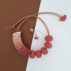 a necklace and earring made out of red beads on a brown string next to a pair of earrings