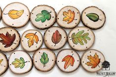 wooden slices with leaves painted on them are arranged in the shape of an autumn tree