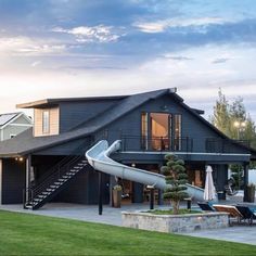 a house with a slide in front of it next to a swimming pool and lawn