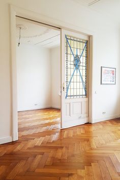 an empty room with wood flooring and white walls in the center is a large open door