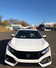 the front end of a white car parked in a parking lot