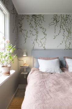 a bed sitting next to a window in a bedroom under a wallpapered with vines