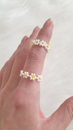 a person's hand with a ring made out of tiny white and yellow flowers