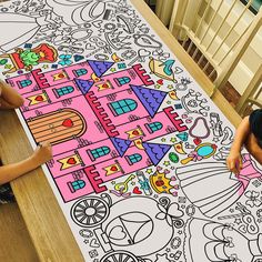 two children are sitting at a table with a large coloring book on top of it