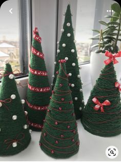 three green christmas trees with bows and pearls on them, sitting in front of a window