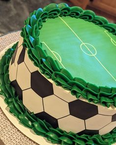 a green and black cake with soccer balls on it