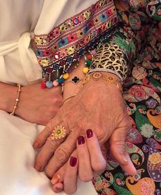 two women holding hands with different colored bracelets on their wrists and wearing matching rings