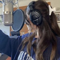 a woman wearing headphones is recording in front of a microphone