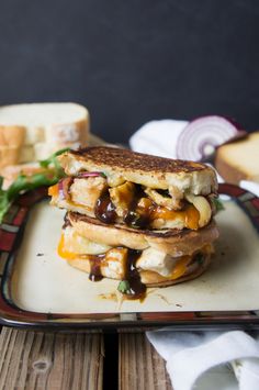 a grilled cheese sandwich on a plate next to some bread and vegetables with sauce