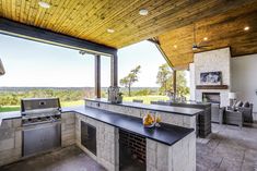 an outdoor kitchen with grill, sink and seating area overlooking the countryside in the distance