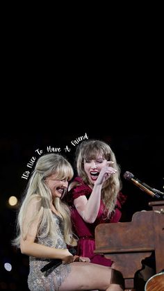 two women sitting next to each other on top of a piano