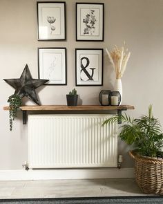 some plants are sitting on top of a radiator in front of three framed pictures