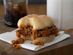 a sloppy joe sandwich sitting on top of a white napkin next to a soda bottle