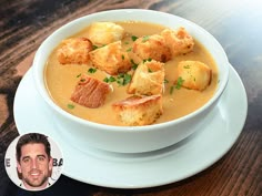 a white bowl filled with soup and croutons on top of a wooden table