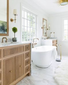 a large white bath tub sitting under a bathroom mirror