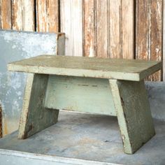 an old wooden bench sitting in front of a wall