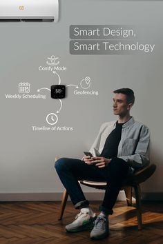 a man sitting in a chair looking at his cell phone with smart technology on the wall behind him