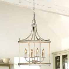 a chandelier hanging from the ceiling in a room with white walls and cabinets