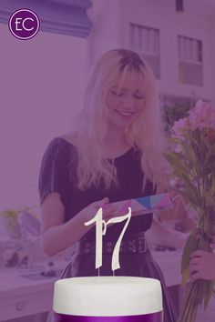 a woman standing next to a cake with the number 17 on it and flowers in front of her