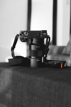 a camera sitting on top of a table next to a bag with a strap around it