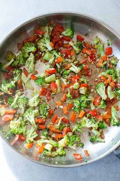 broccoli and tomatoes are being cooked in a pan