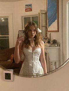 a woman in a white corset taking a selfie with her cell phone