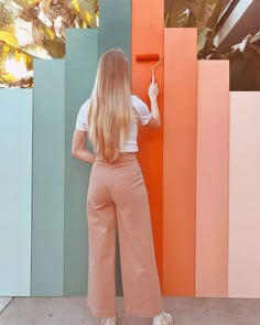 a woman standing in front of a colorful wall with her back to the camera and holding onto an orange handle