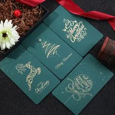 four christmas cards in a gift box with a red ribbon on the floor next to them