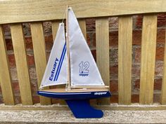 a toy sailboat sitting on top of a wooden bench