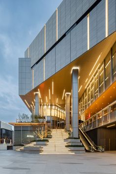 the outside of a building with stairs leading up to it and lights shining on the side