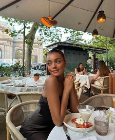 a woman sitting at an outdoor restaurant table with food on the plate in front of her