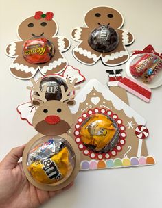 someone holding up some candy in front of gingerbreads and christmas decorations on a table