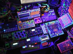 a table topped with lots of electronic devices and wires covered in neon colors on top of it