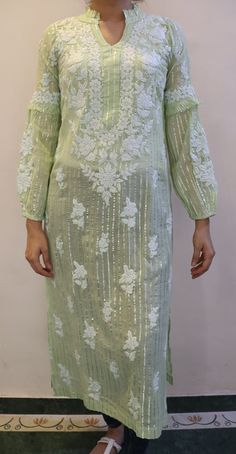 This Exquisite tunic combines the timeless charm of Chikankari embroidery with the contemporary allure of cotton and lurex fabric. Its  a perfect blend of traditional craftsmanship and modern style. With its intricate detailing of ruffled collar, balloon sleeves, beautiful embroidery and subtle shimmer, this tunic adds a touch of elegance to any outfit. Lightweight and comfortable, its ideal for both casual and festive occasions. The addition of lurex threads enhances the tunics allure, creating a subtle shimmer that catches the light and adds a modern twist to the classic Chikankari style.  Made from 100% pure cotton Mulmul. Length - 46/47 inches Sizes -  S - fits bust 34 M - fits bust 36 L - fits bust 38 XL - fits bust 40 0X - fits bust 42 1X - fits bust 44 Prewashed. Preshrunk. Summer Cotton Kurta With Embroidered Sleeves, Festive Spring Blouse Piece, Festive Long Sleeve Kaftan, Bollywood Style Kurta With Mirror Work For Spring, Spring Green Tunic With Chikankari Embroidery, Long Sleeve Cotton Silk Dress With Intricate Embroidery, Fitted Long Sleeve Kaftan With Floral Embroidery, Spring Long Sleeve Tunic With Intricate Embroidery, Spring Tunic With Intricate Embroidery And Long Sleeves