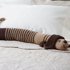 a crocheted stuffed animal laying on top of a bed next to two pillows