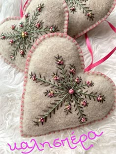 three heart shaped ornaments with pink ribbon on white fur