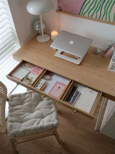 an apple computer sitting on top of a wooden desk next to a chair and lamp