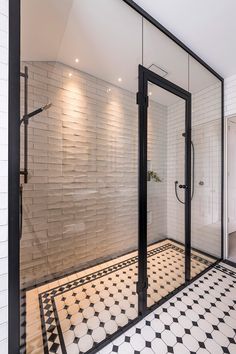 a bathroom with black and white tiles on the floor, glass doors to walk in shower