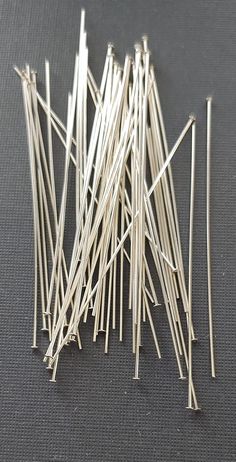 several pieces of silver colored pins on a black surface with one piece missing from the top