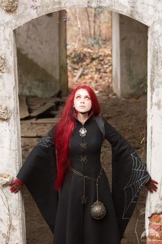 a woman with long red hair wearing a black dress and holding her hands on her hips