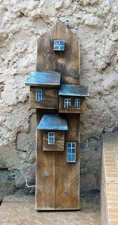 a wooden house made out of wood sitting on top of a brick floor next to a stone wall