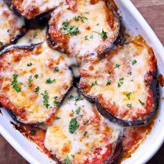 an oval white dish filled with eggplant covered in cheese and parmesan