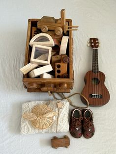 a wooden box filled with assorted items on top of a white surface next to a pair of brown shoes