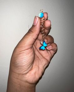 a woman's hand holding a chain with two blue butterflies on it