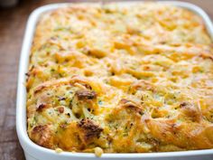 a casserole dish with cheese and broccoli in it on a wooden table