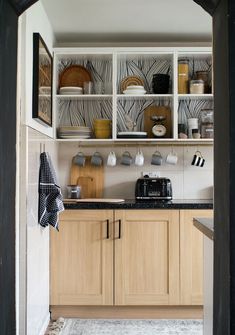 a kitchen with wooden cabinets and chalk writing on the wall behind it, as well as an open door leading to another room